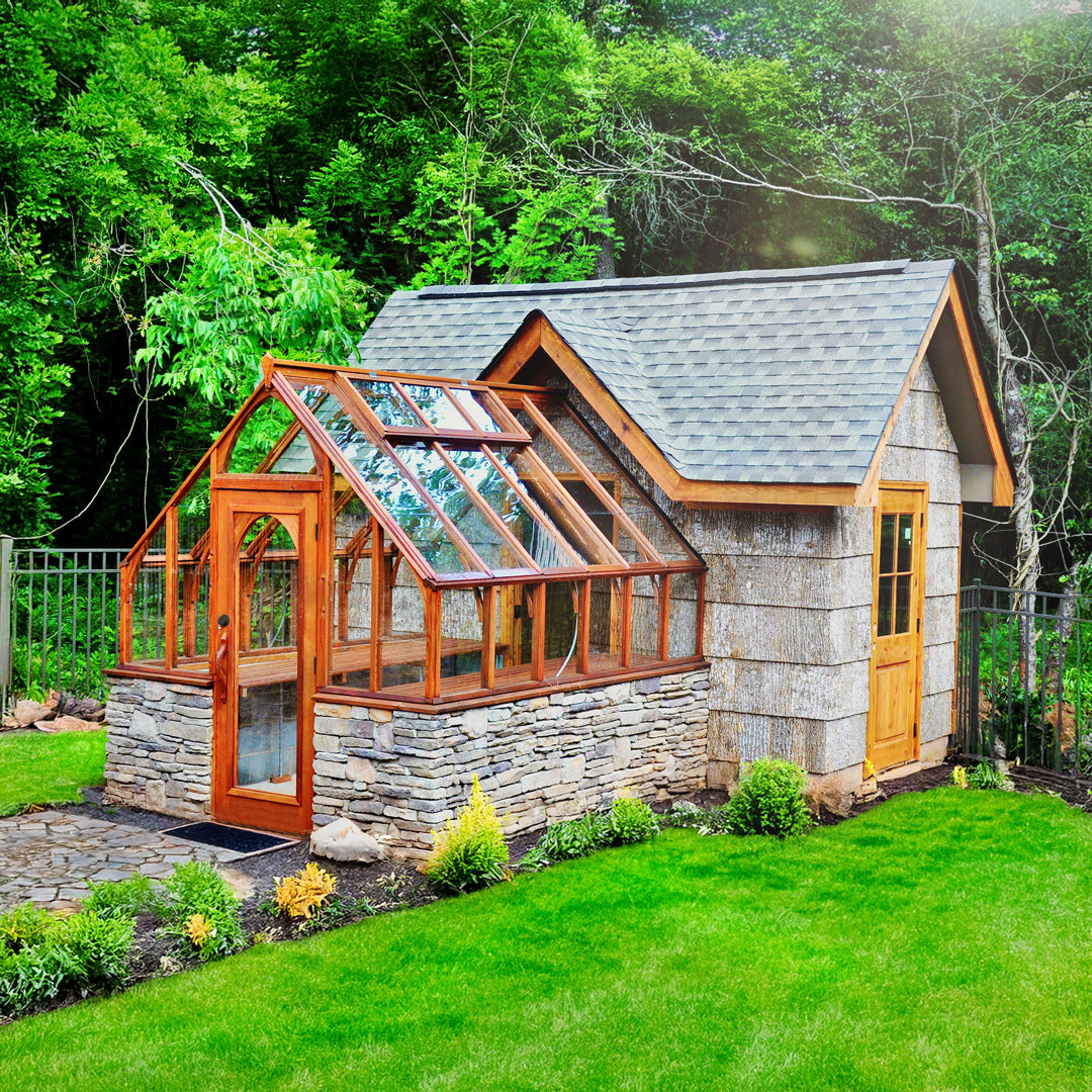 Stone building with attached greenhouse in a lush green garden