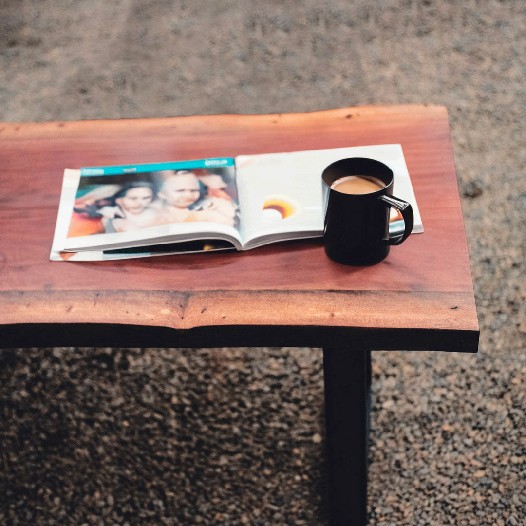 Open magazine with a coffee cup on a wooden table outdoors