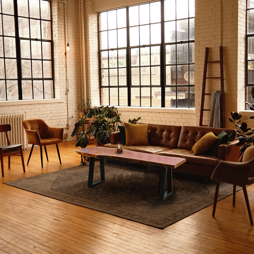 Living room with brown sectional sofa, wooden slab coffee table, and large windows.