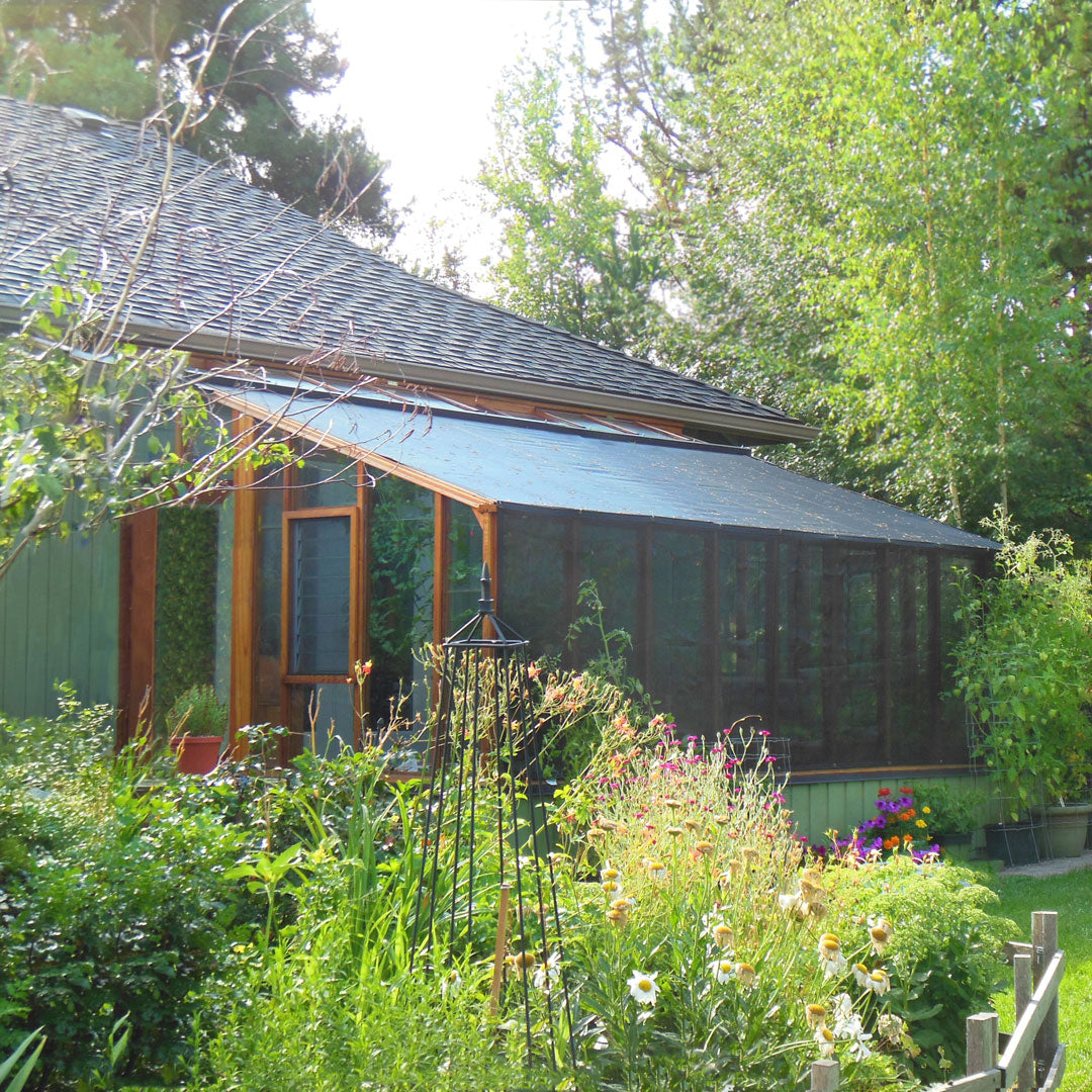 Green house with a garden in front, surrounded by trees