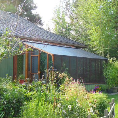 Green house with a garden in front, surrounded by trees