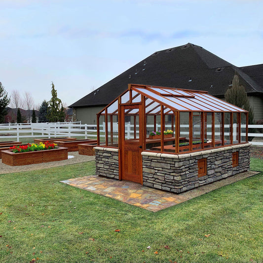 Wooden greenhouse with stone foundation on a grassy lawn