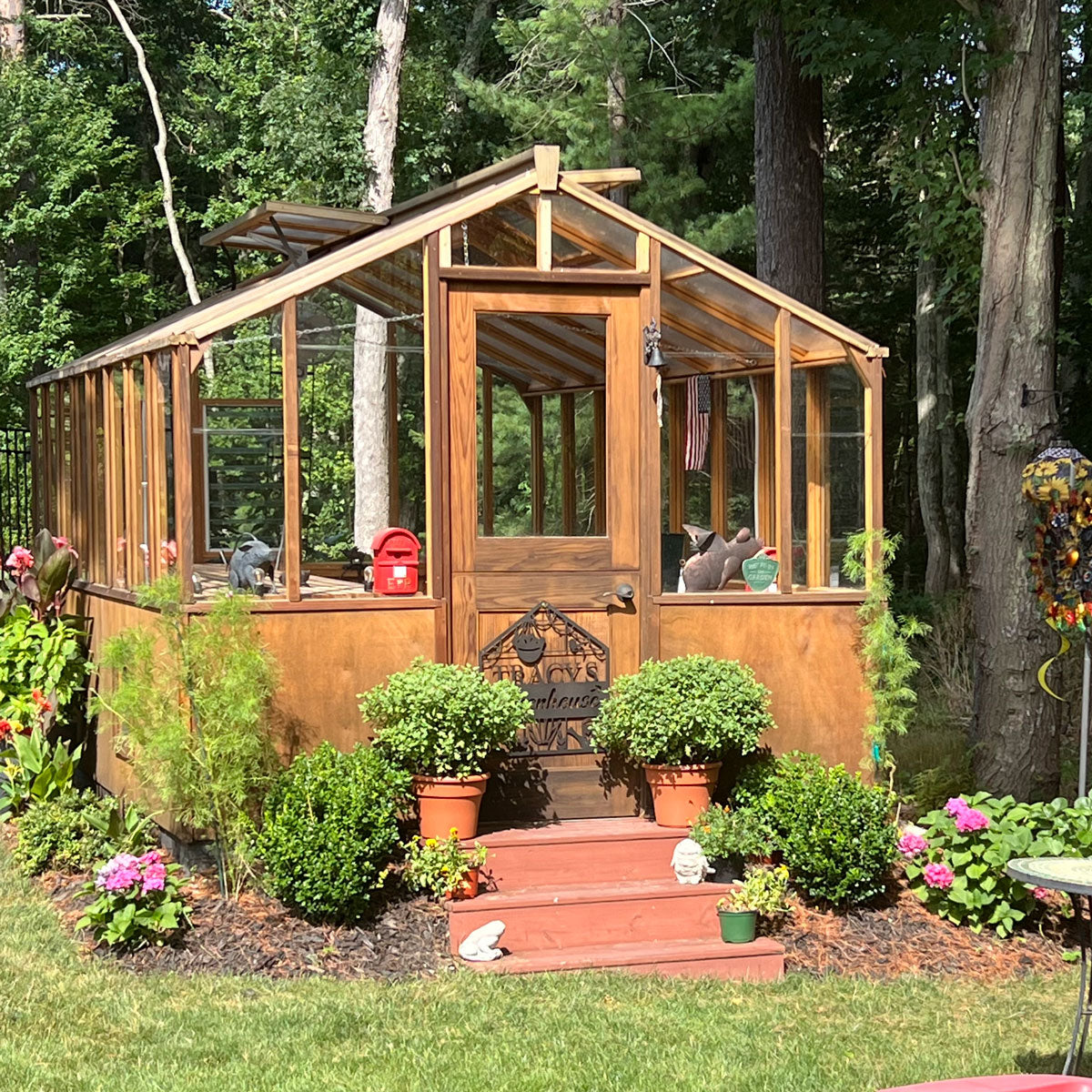 Wooden greenhouse with plants and flowers in a garden setting