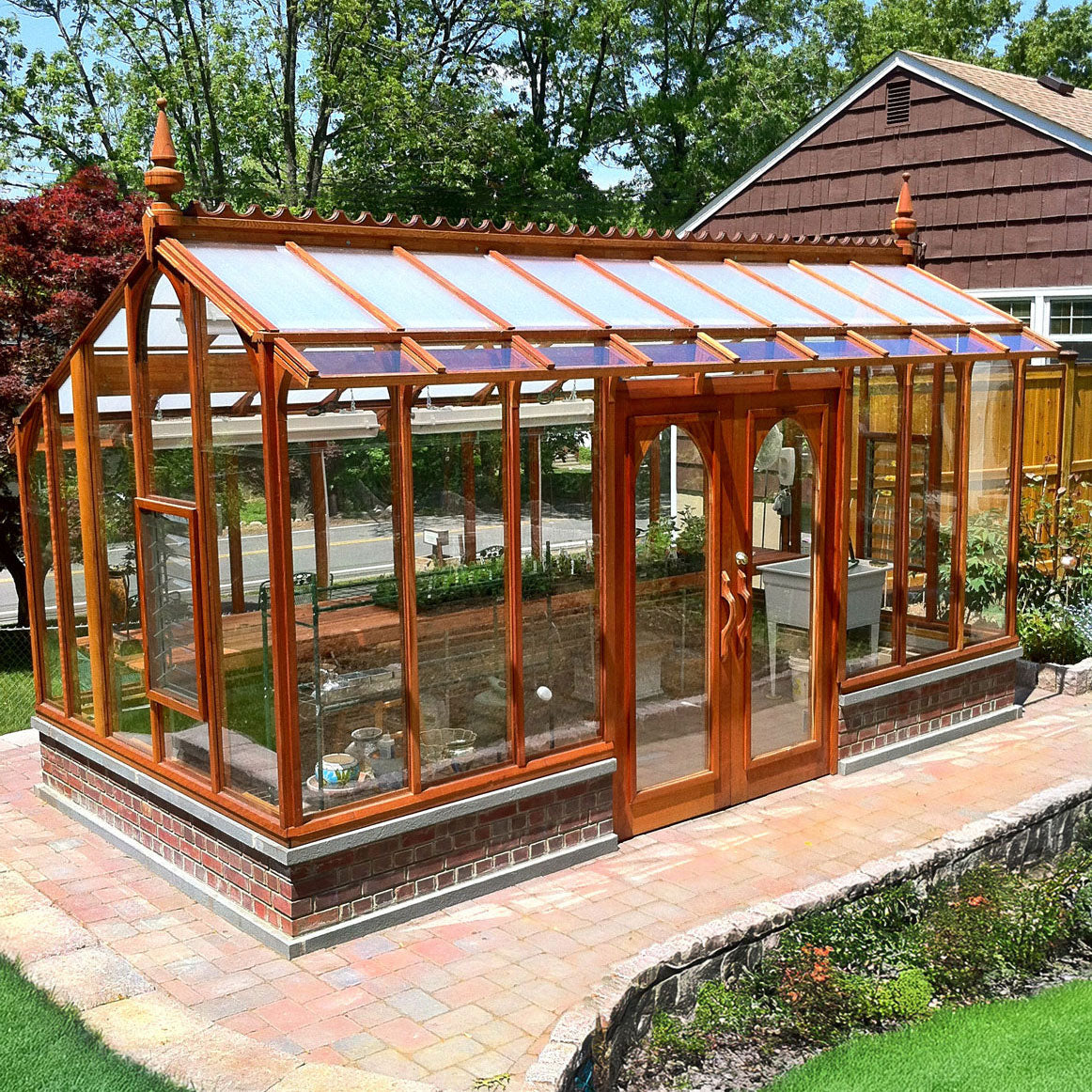 Wooden framed greenhouse with glass panels on a patio